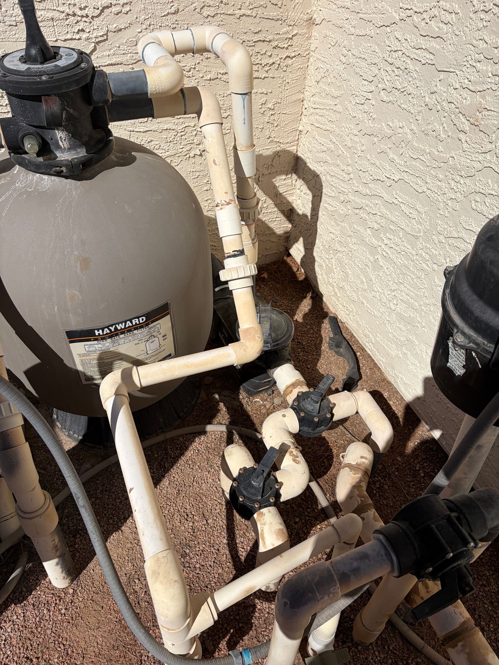 An aging equipment pad with sun-worn plumbing — the kind of before we see a lot
